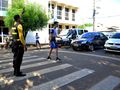 Agente de trânsito orienta pedestre durante travessia segura na faixa na Rua Simplício Moreira, no Centro