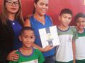 Elaine Ruas de Lima, merendeira da Escola Tia Emília recebendo o livro do FNDE com as melhores receitas do Brasil