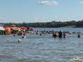 Banhistas aproveitam o domingo de sol na Praia do Cacau durante o Verão da Prefs 2025, que conta com estrutura reforçada, segurança e programação cultural para toda a família.